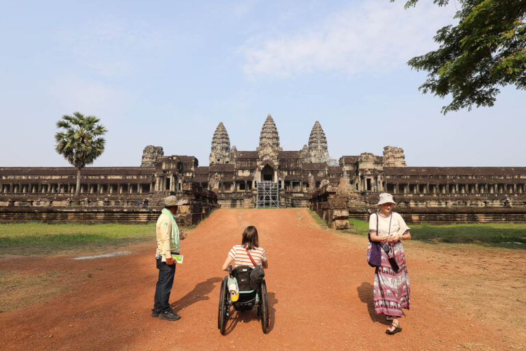 Wheelchair user visiting Angkor Wat courtyard with guide in Siem Reap