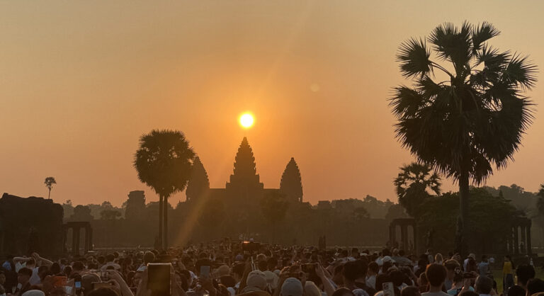 Sun rising directly aligned over the central tower of Angkor Wat during the equinox with a large crowd gathered in the foreground