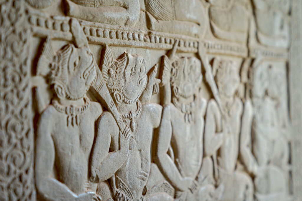Close-up of ancient stone bas-relief carvings depicting mythological figures on the gallery walls of Angkor Wat