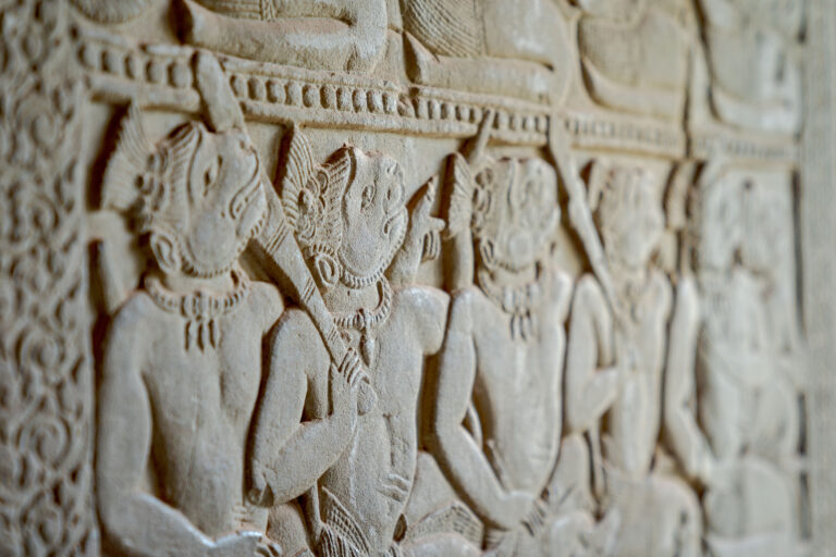 Close-up of ancient stone bas-relief carvings depicting mythological figures on the gallery walls of Angkor Wat