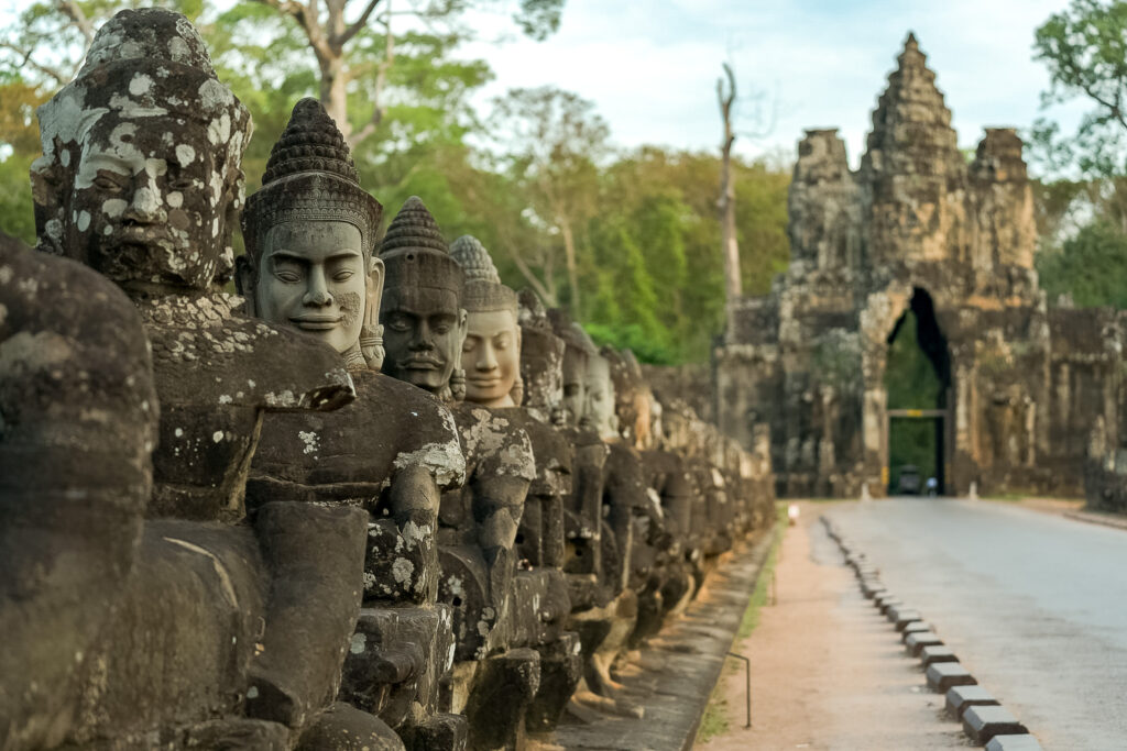 Stone figures lining the Angkor Thom South Gate causeway, including restored replacement faces