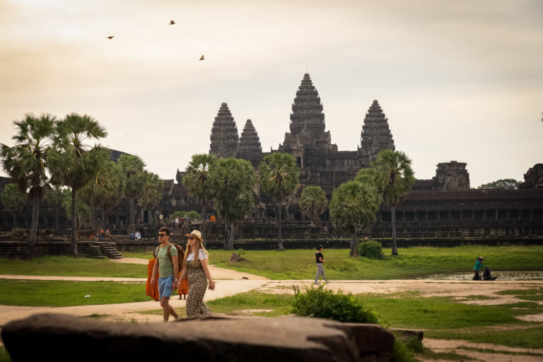 Tourists walking toward Angkor Wat temple across the main causeway in Siem Reap, Cambodia.