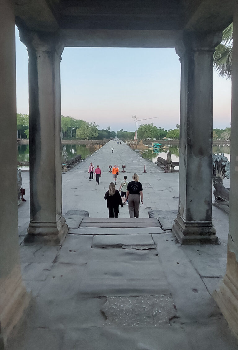 View looking back across the stone causeway bridge through the outer sandstone gate pillars at Angkor Wat