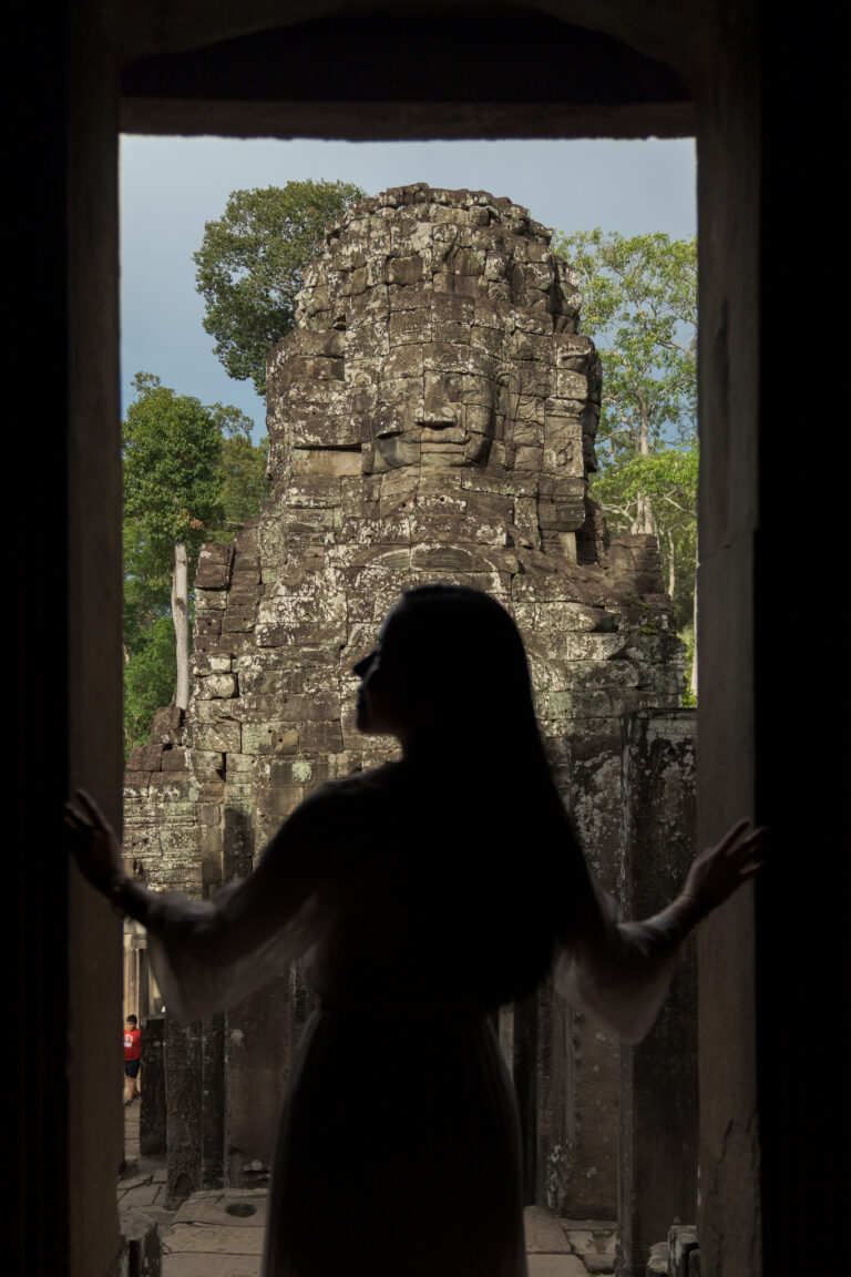 Visitor looking up at a stone face at Bayon Temple while the upper terrace is closed for restoration