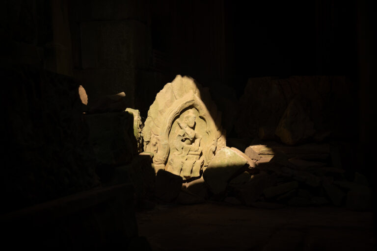 Small stone carving illuminated by sunlight on the ground inside Ta Prohm