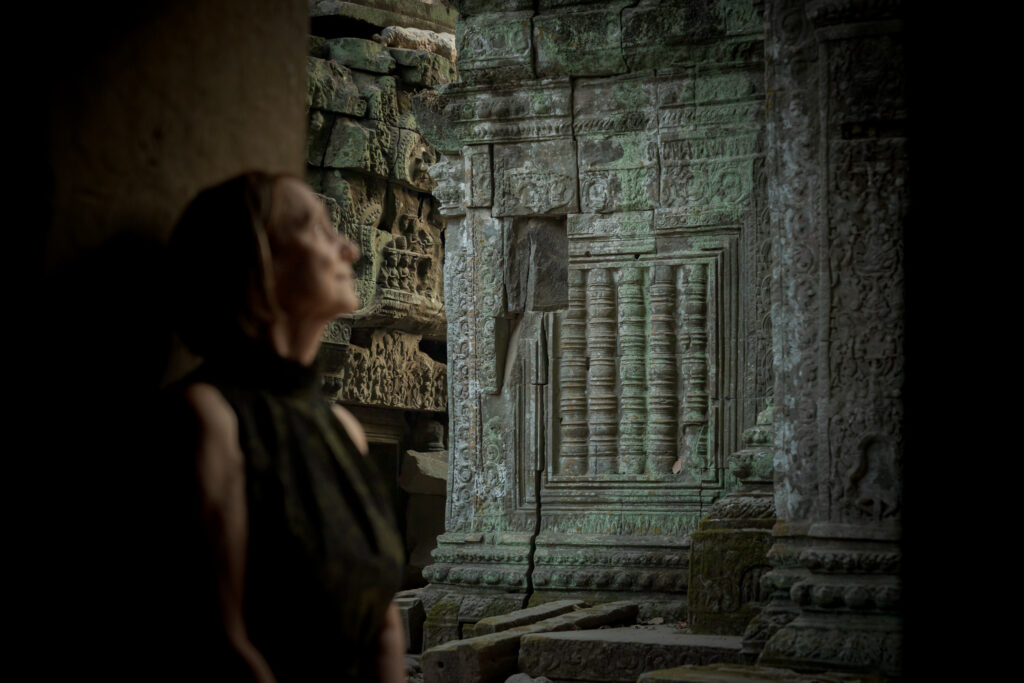 Visitor exploring the intricate galleries inside Ta Prohm temple, Siem Reap, Cambodia