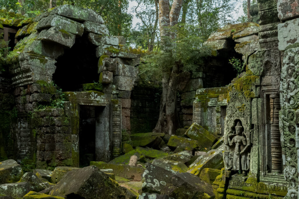 Ruined stone corridors and carved doorway at Ta Nei temple surrounded by jungle