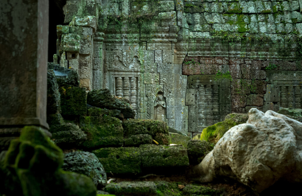 Carved stone doorways and figures framed by the ruins inside Ta Nei temple